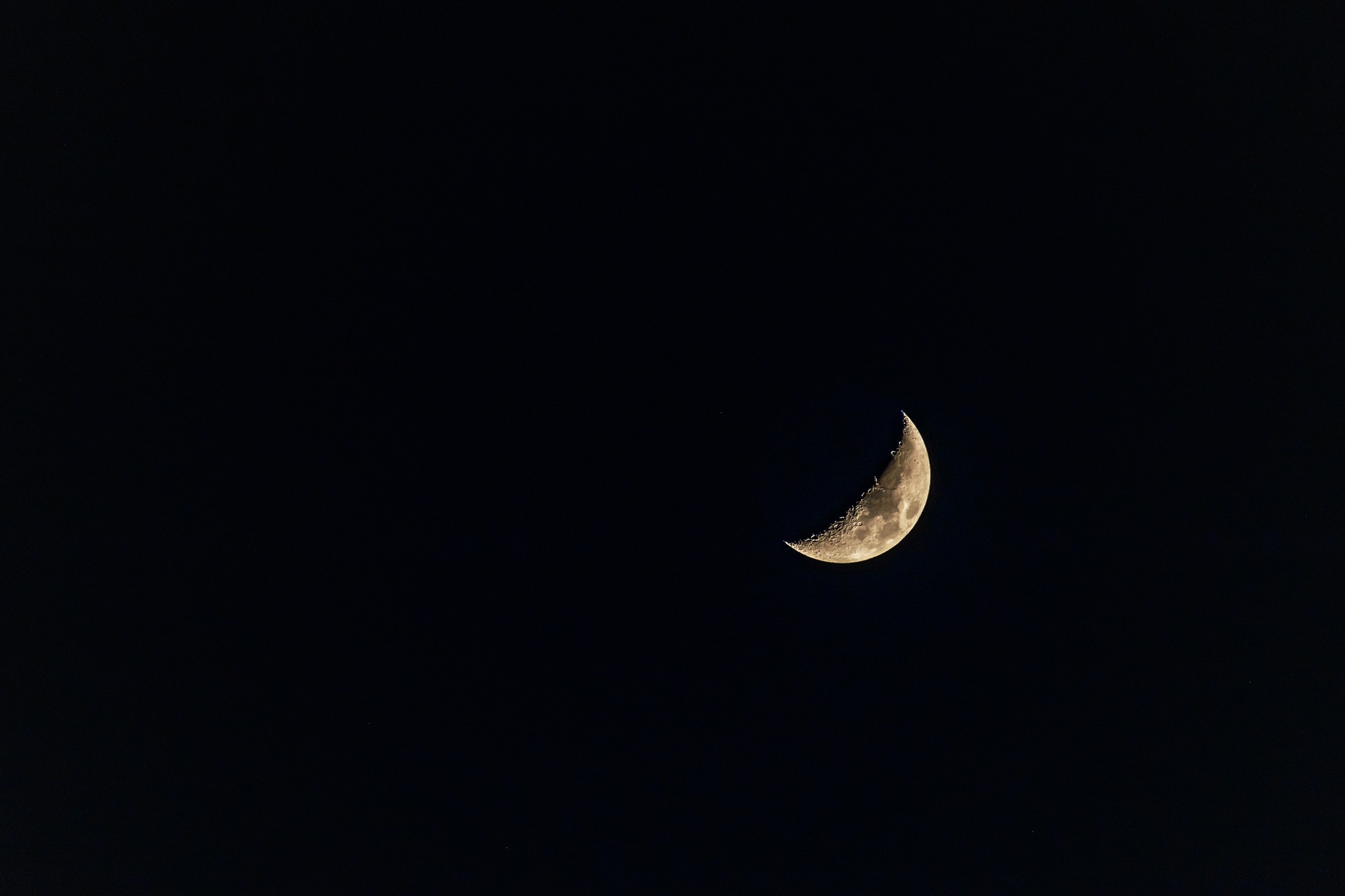 Bild von einem halbbedeckten Mond. Der Himmel ist sehr dunkel.